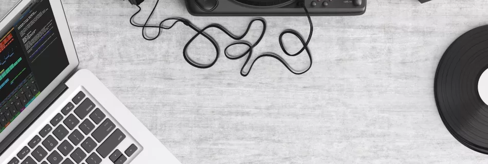 Flat lay of a music workspace with a laptop, headphones, turntable, and speakers on a desk.