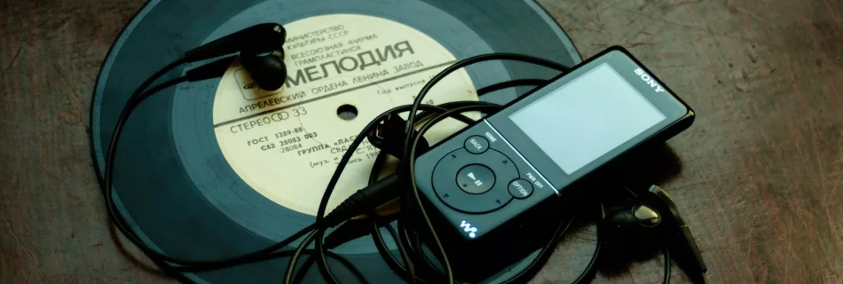 in-ear headphones plugged in black Sony Walkman on vinyl record