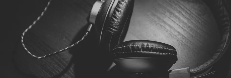 grayscale photo of corded headphones on table